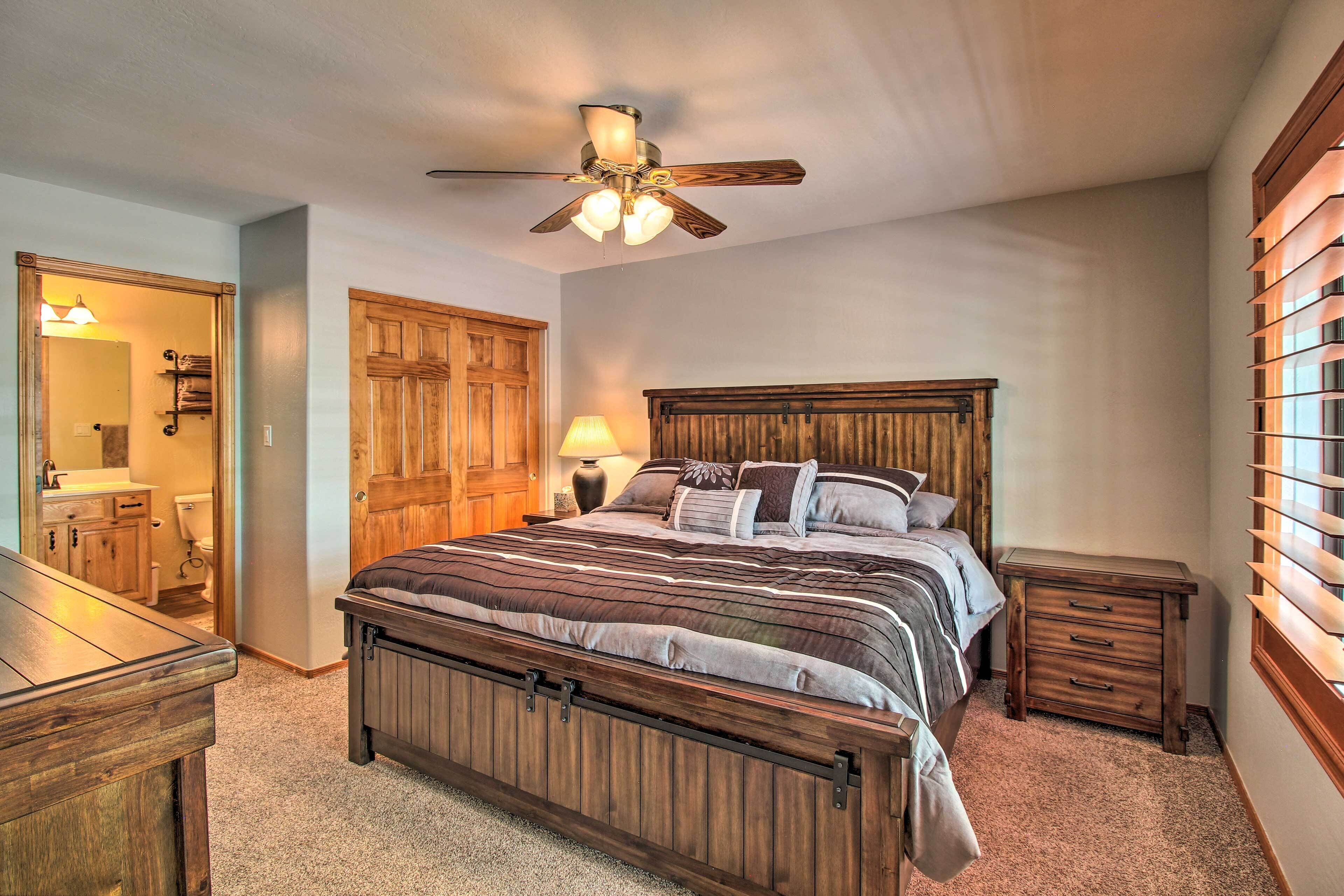 A bedroom with a wooden bed, a ceiling fan, a nightstand, and a window with blinds.