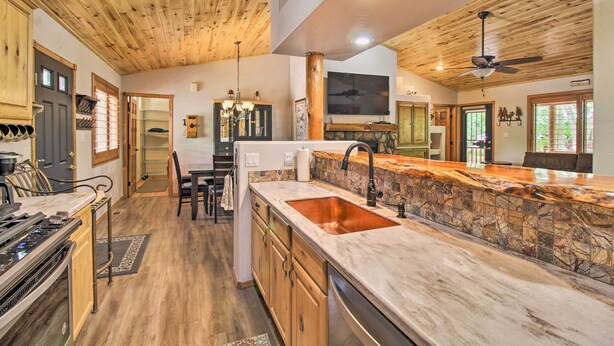 A spacious kitchen with a stone backsplash, wooden ceiling, and a large island with a sink. - 3 Mi to Trails: Woodsy Retreat in Overgaard! (Overgaard)