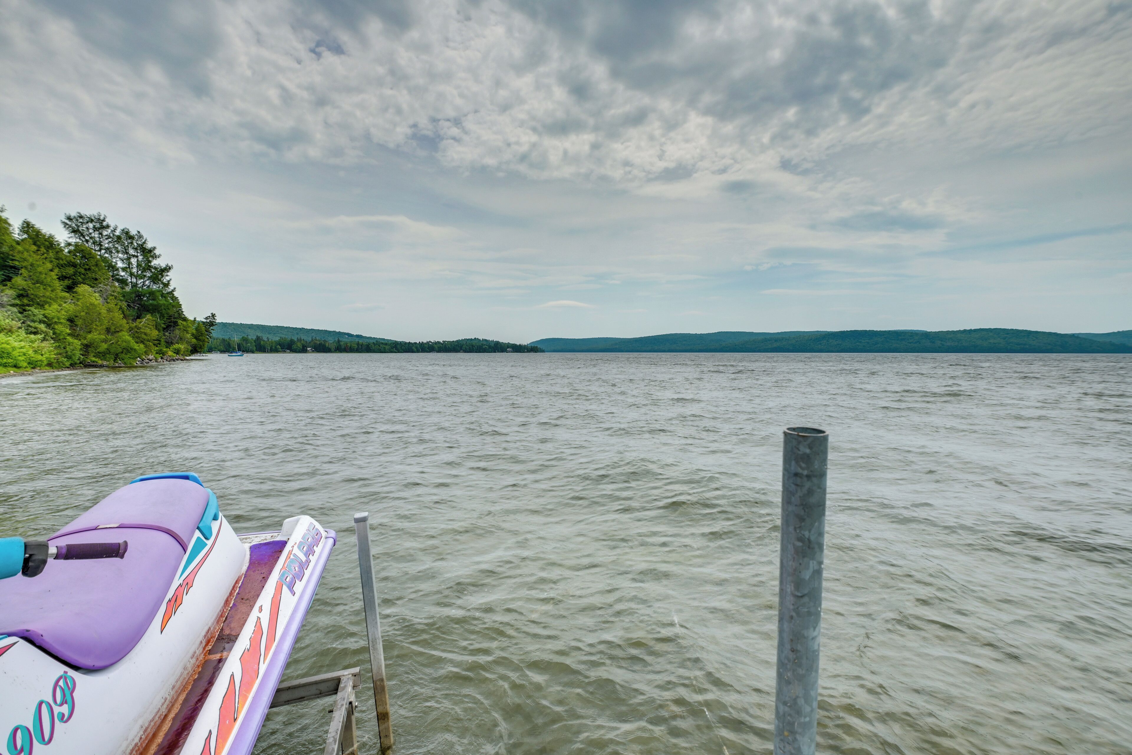 A boat docked at a pier with a view of a lake and distant hills.