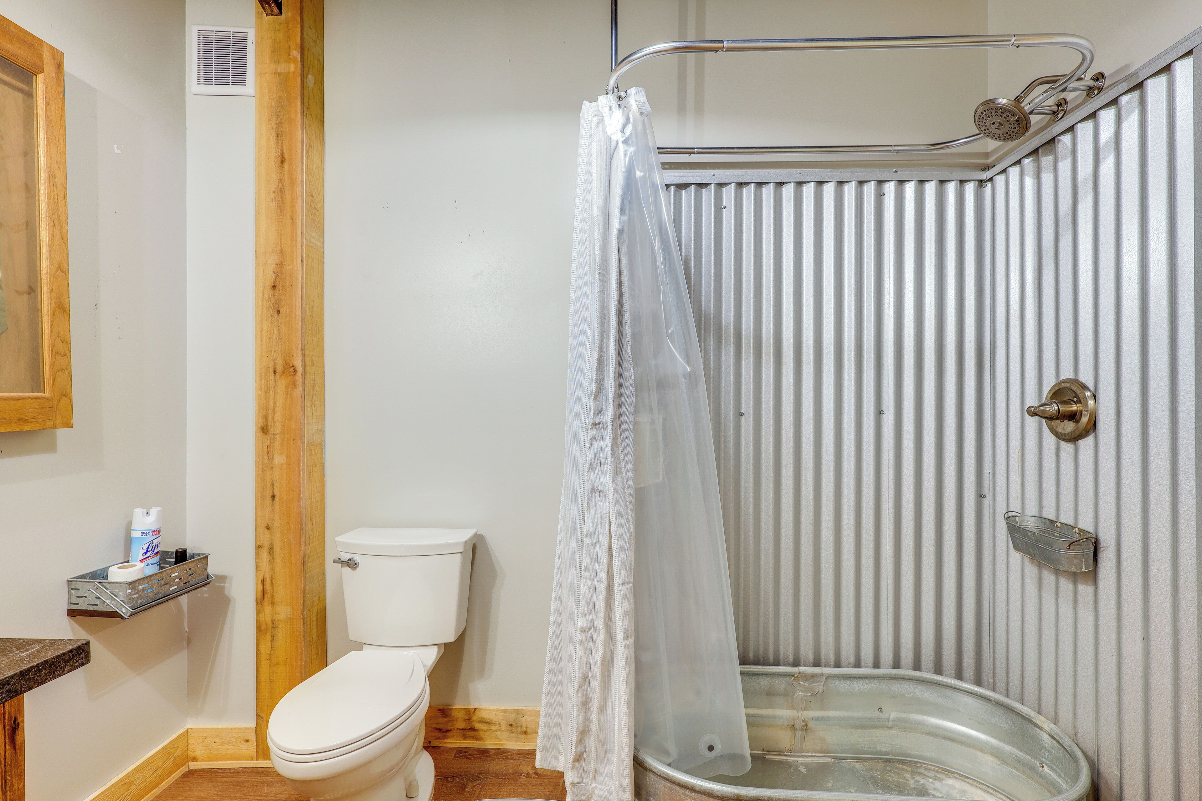 Un baño pequeño y funcional con inodoro, ducha y lavabo de metal.