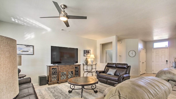 A living room with a ceiling fan, a flat-screen TV, leather sofas, a coffee table, and a fireplace.