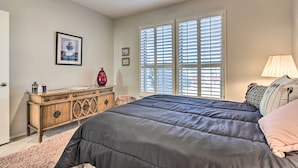 A bedroom with a bed, dresser, and window with blinds.