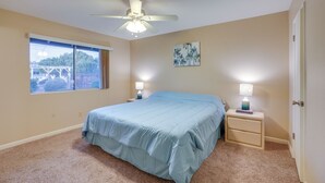 Une chambre à coucher avec un lit, un ventilateur de plafond, une fenêtre et deux lampes de chevet.