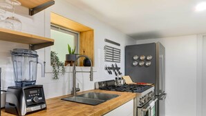 Cozinha moderna com fogão a gás embutido, eletrodomésticos de aço inoxidável e bancada de madeira.