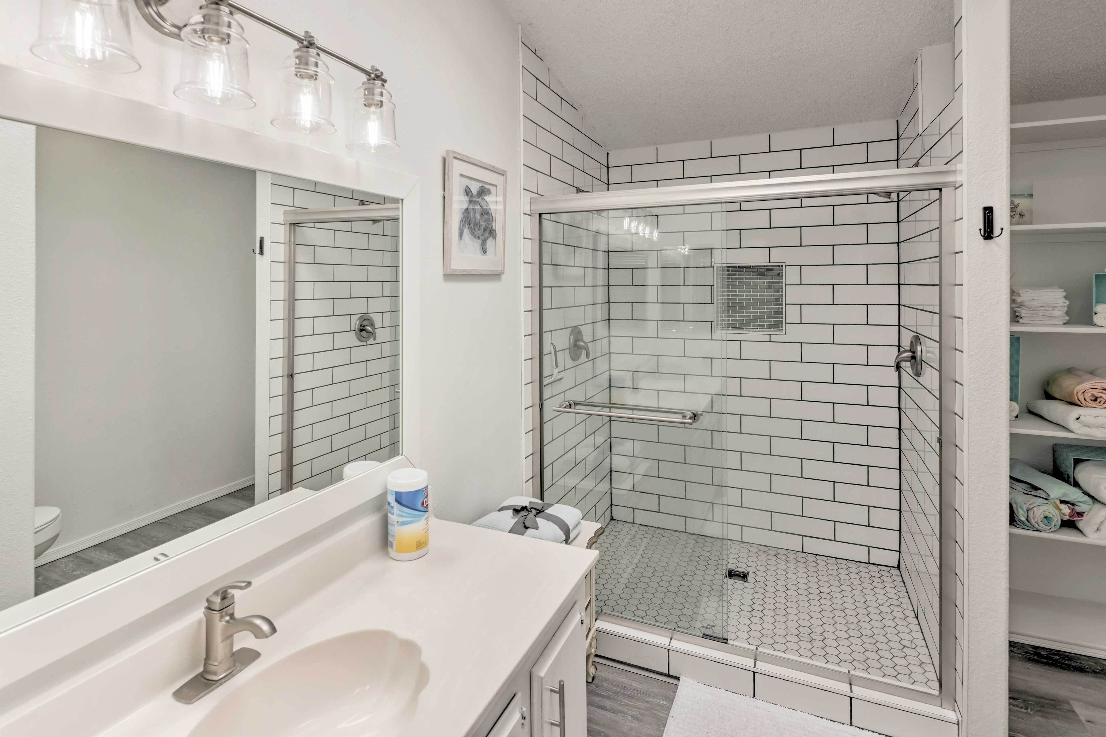 Une salle de bain moderne avec une douche à parois de verre, un lavabo blanc et un grand miroir.