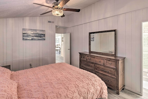A bedroom with a large bed, a dresser, a ceiling fan, and a painting on the wall. - Private Dock, Tons of Fun! Home on Colorado River (Bullhead City)