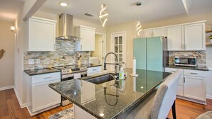 A modern kitchen with a central island, stainless steel appliances, and a backsplash with mosaic tiles. - Wooded Pottsboro Escape ~ 1 Mi to Lake Texoma (Pottsboro)