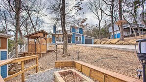 A residential area with a wooden deck, a stone fire pit, and a house with blue siding and a balcony. - Wooded Pottsboro Escape ~ 1 Mi to Lake Texoma (Pottsboro)