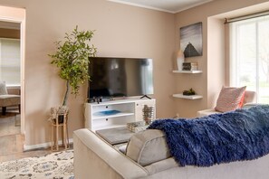 A modern living room with a flat-screen TV, a sofa, a coffee table, and a decorative plant. - Pet-friendly Mayfield Heights Vacation Rental! (Mayfield Heights)
