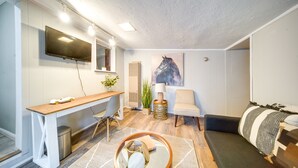 A modern living room with a wooden desk, a sofa, a TV mounted on the wall, and a horse painting on the wall. - Pet-friendly Mayfield Heights Vacation Rental! (Mayfield Heights)