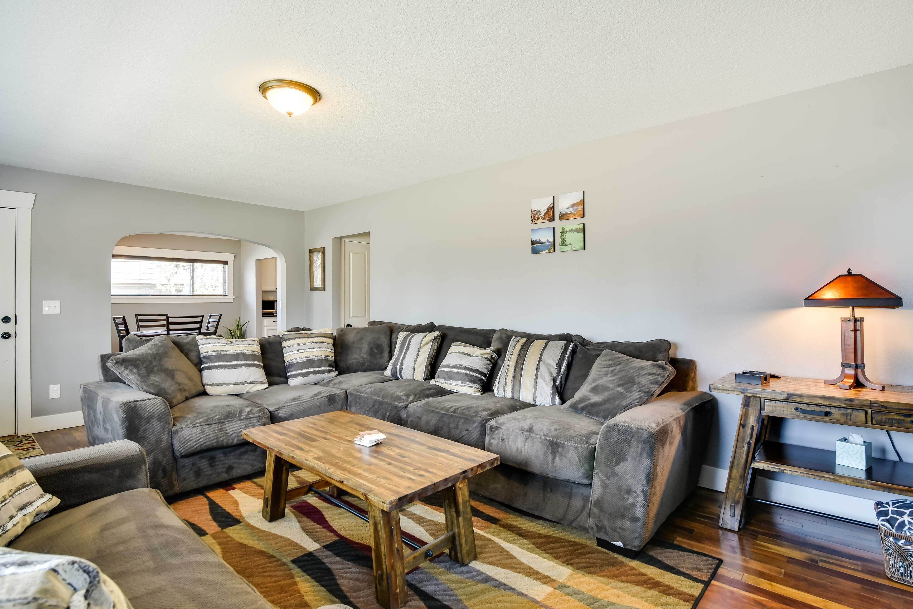 A living room with a sectional sofa, a wooden coffee table, and a lamp on a side table.