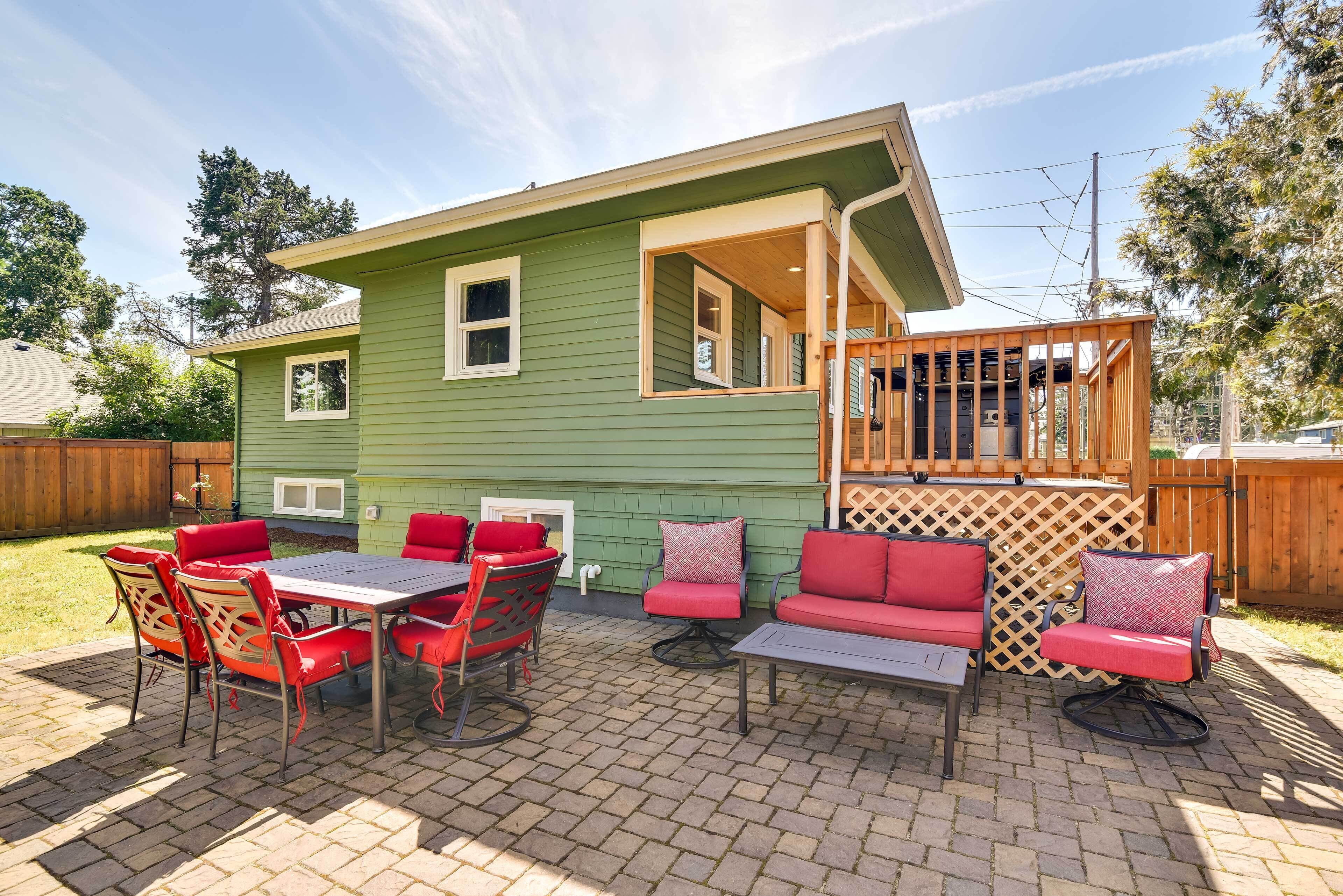 Une maison verte dotée d’un patio comprenant une table et des chaises, un canapé et une terrasse en bois.