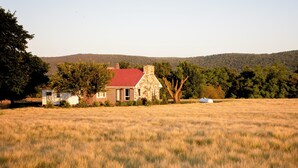 Ein Haus aus Stein mit rotem Dach und einem Feld im Vordergrund.