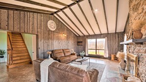 Ein geräumiges Wohnzimmer mit einer braunen Ledersofa, einer Holztreppe und einer Steinwand.