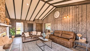 Ein rustikales Wohnzimmer mit Holzwänden, Ledersofas, einem Couchtisch und einer Wanduhr.