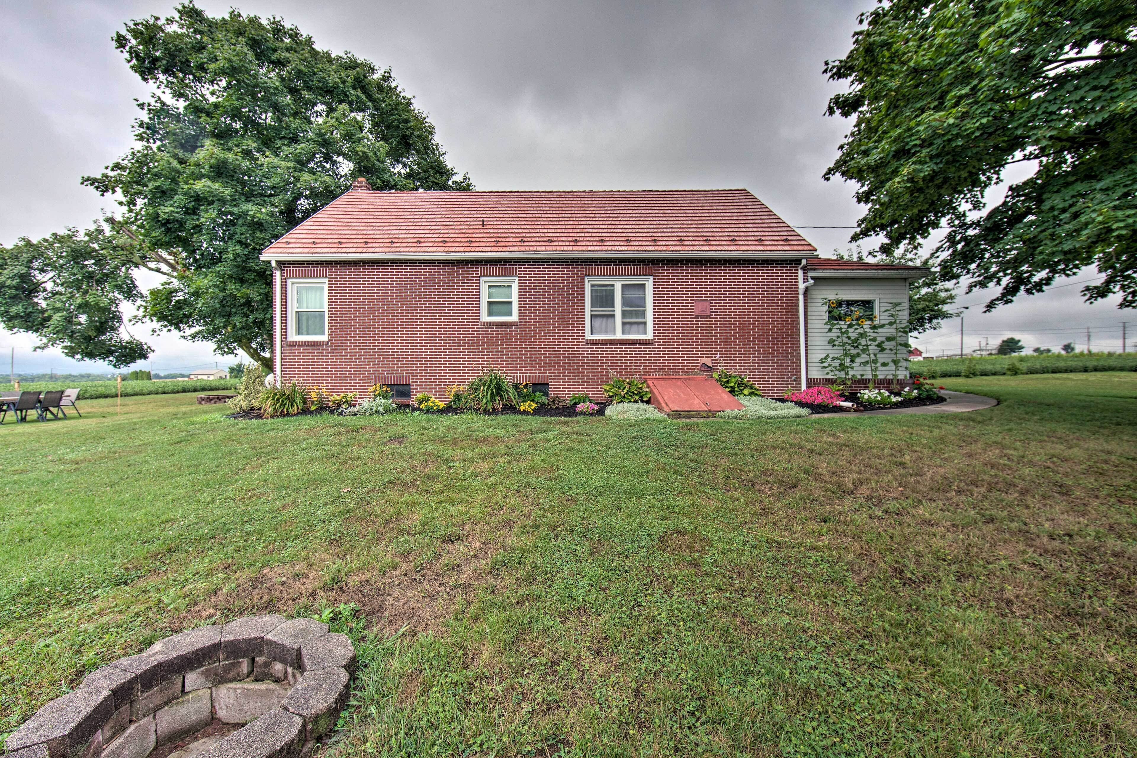 A single-story brick house with a red roof, a small porch, and a well-maintained lawn.
