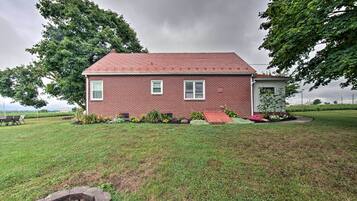 A single-story brick house with a red roof, a small porch, and a well-maintained lawn.