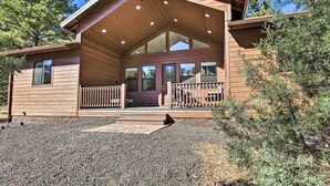 Une cabane en bois dotée d’un porche couvert, de grandes fenêtres et d’une allée en gravier.