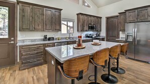 Une cuisine moderne avec des meubles en bois, un plan de travail en granit et un réfrigérateur en acier inoxydable.