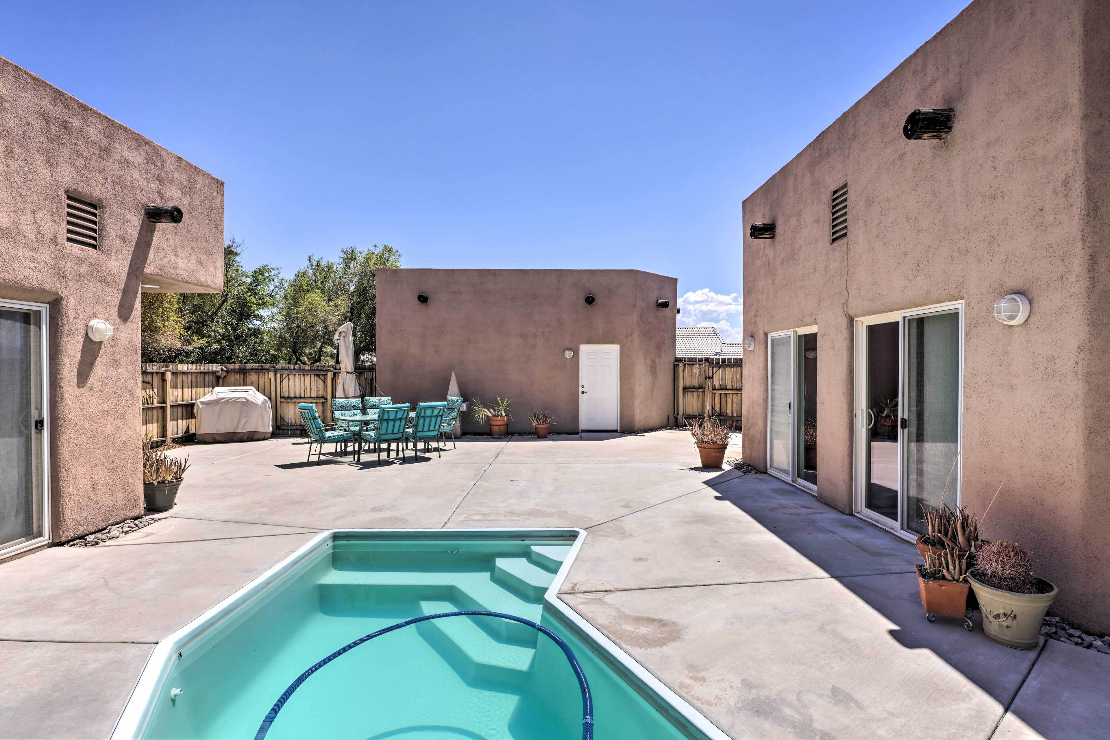 Un cortile con piscina, mobili da patio e piante in vaso.