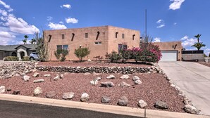 A modern building with a stucco exterior, a stone retaining wall, and a parking area.