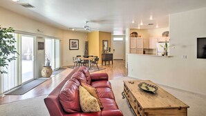 A spacious living room with a red leather sofa, a wooden coffee table, and a dining area with a table and chairs.