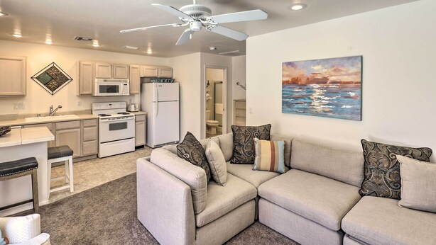 A modern kitchen with white appliances, a ceiling fan, and a dining area with a light-colored sofa.