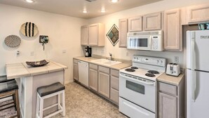 A modern kitchen with a central island, built-in appliances, and light wood cabinetry.
