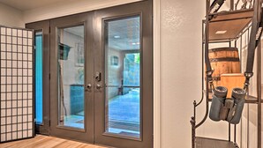 Una habitación con puerta de vidrio corredera que da a un balcón, piso de madera y un perchero metálico con binoculares.