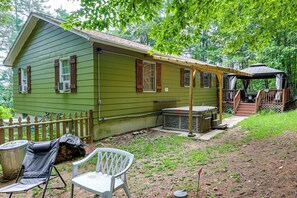A green cabin with a porch, a covered outdoor seating area, and a small deck. - Rustic Adirondacks Home w/ Hot Tub & Lake Access! (Chestertown)