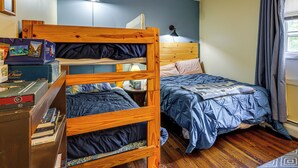 A bunk bed with a wooden headboard, a desk with books, a lamp, and a window with curtains. - Rustic Adirondacks Home w/ Hot Tub & Lake Access! (Chestertown)