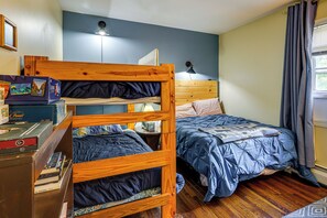 A bunk bed with a wooden headboard, a desk with books, a lamp, and a window with curtains. - Rustic Adirondacks Home w/ Hot Tub & Lake Access! (Chestertown)