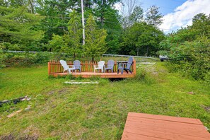 A wooden deck with outdoor seating and a view of a forested area. - Rustic Adirondacks Home w/ Hot Tub & Lake Access! (Chestertown)