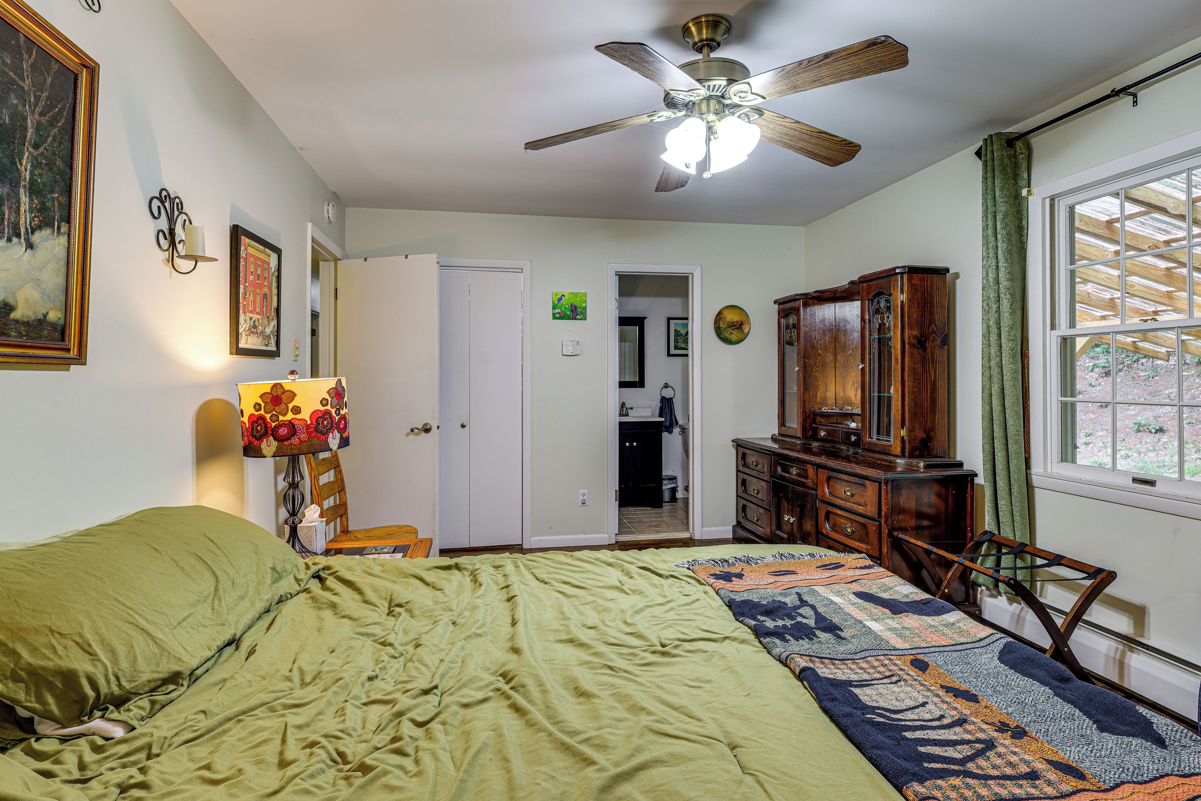 A bedroom with a bed, a ceiling fan, a dresser, and a window.