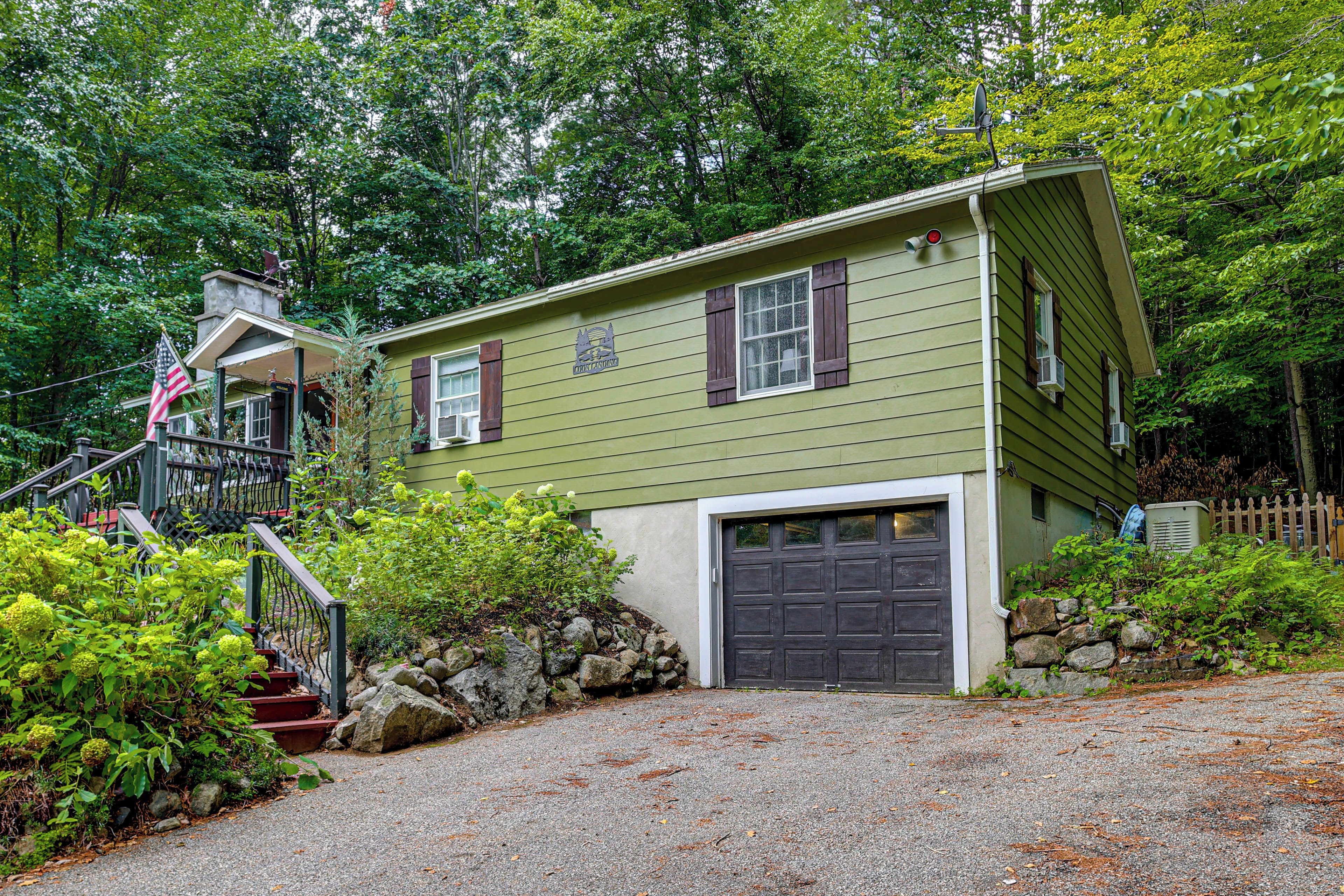 A two-story house with a front porch, a garage, and a flag.
