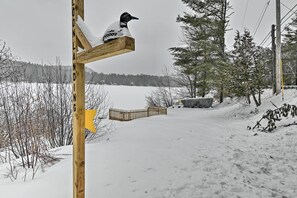 A wooden signpost with a bird perched on it, surrounded by snow-covered ground and trees. - Rustic Adirondacks Home w/ Hot Tub & Lake Access! (Chestertown)