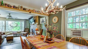 A spacious dining area with a long wooden table, surrounded by chairs, and a chandelier with antler decorations. - Rustic Adirondacks Home w/ Hot Tub & Lake Access! (Chestertown)