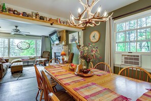 A spacious dining area with a long wooden table, surrounded by chairs, and a chandelier with antler decorations. - Rustic Adirondacks Home w/ Hot Tub & Lake Access! (Chestertown)