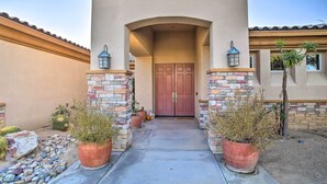 A house entrance with a concrete pathway, a double door, and two potted plants on either side. - Spacious Palm Desert Retreat w/ Outdoor Oasis! (Palm Desert)
