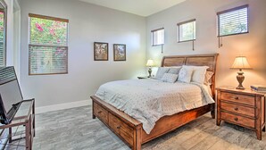 A bedroom with a wooden bed, two bedside tables with lamps, a ceiling fan, and three windows with blinds. - Spacious Palm Desert Retreat w/ Outdoor Oasis! (Palm Desert)