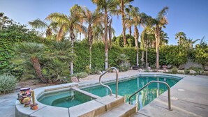 A swimming pool with a concrete edge and steps leading into the water, surrounded by palm trees and various plants. - Spacious Palm Desert Retreat w/ Outdoor Oasis! (Palm Desert)