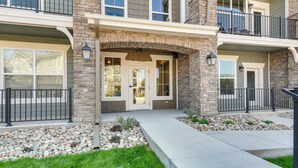 A multi-story building with a stone facade, a covered entryway, and a balcony with outdoor seating. - Elegant Loveland Condo < 5 Mi to Old Town! (Loveland)