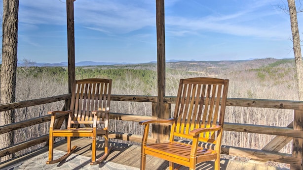 Eine Holzterrasse mit zwei Schaukelstühlen mit Blick auf eine natürliche Landschaft.
