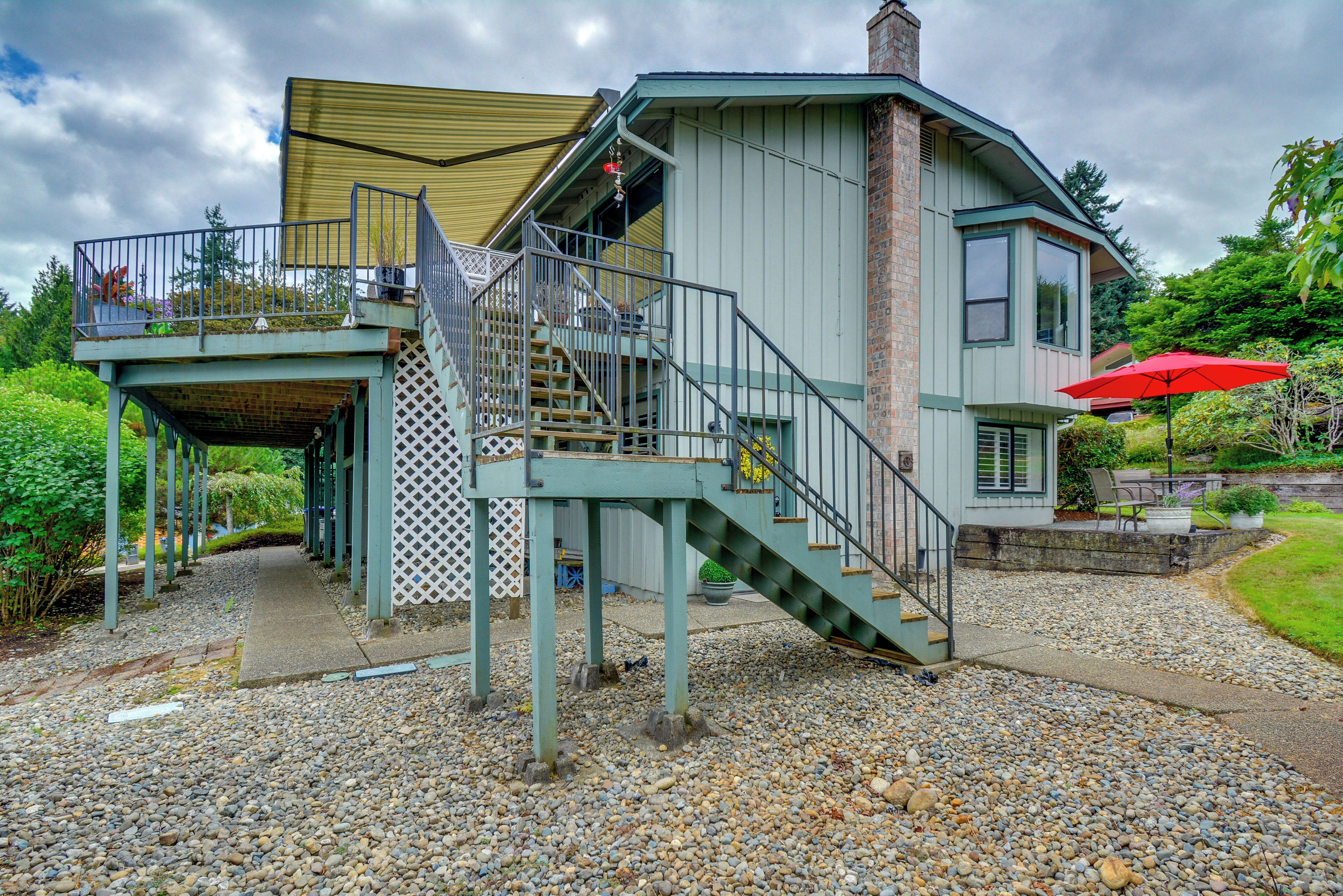 A house with a covered outdoor area, a staircase, and a red umbrella.
