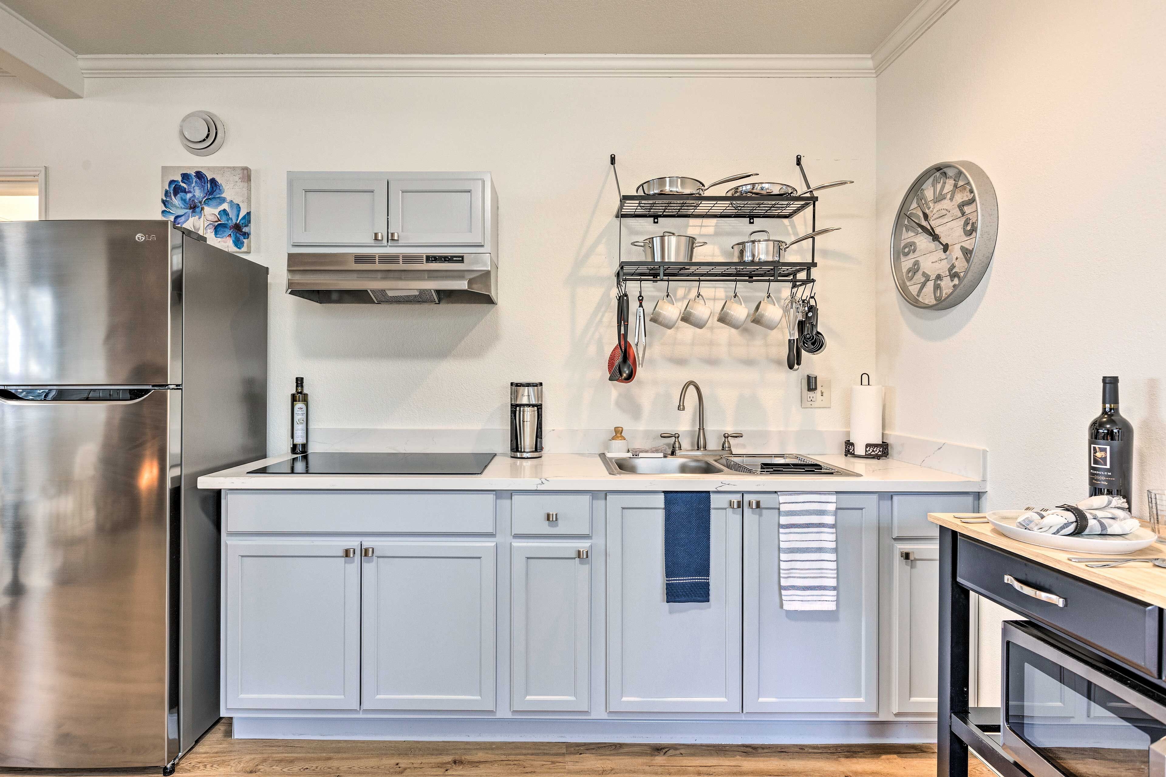 A modern kitchen with white cabinets, stainless steel appliances, and a clock on the wall.