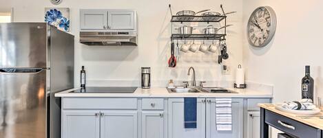 A modern kitchen with white cabinets, stainless steel appliances, and a clock on the wall.