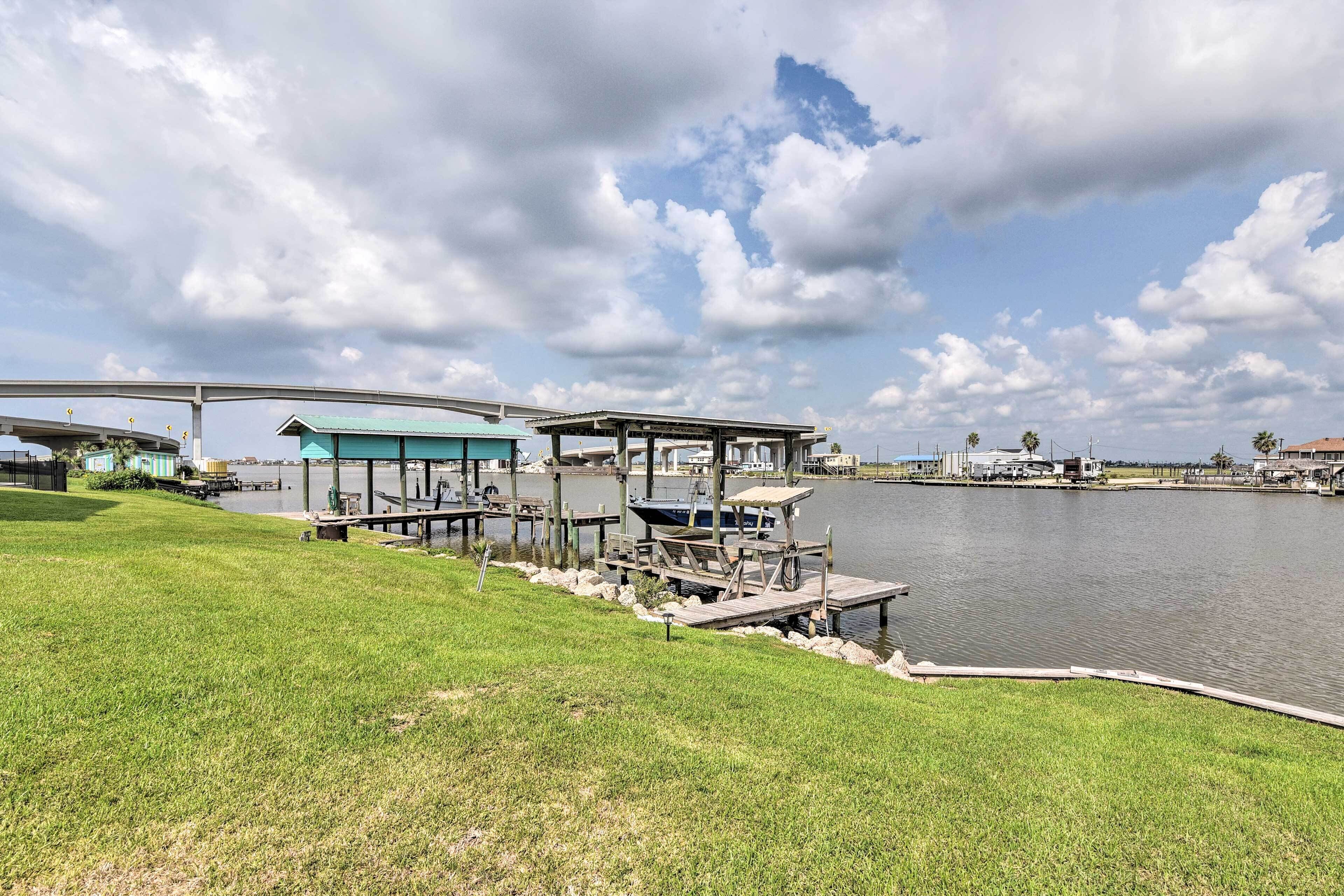 A lakeside area with a dock, a covered seating area, and a building with a green roof.
