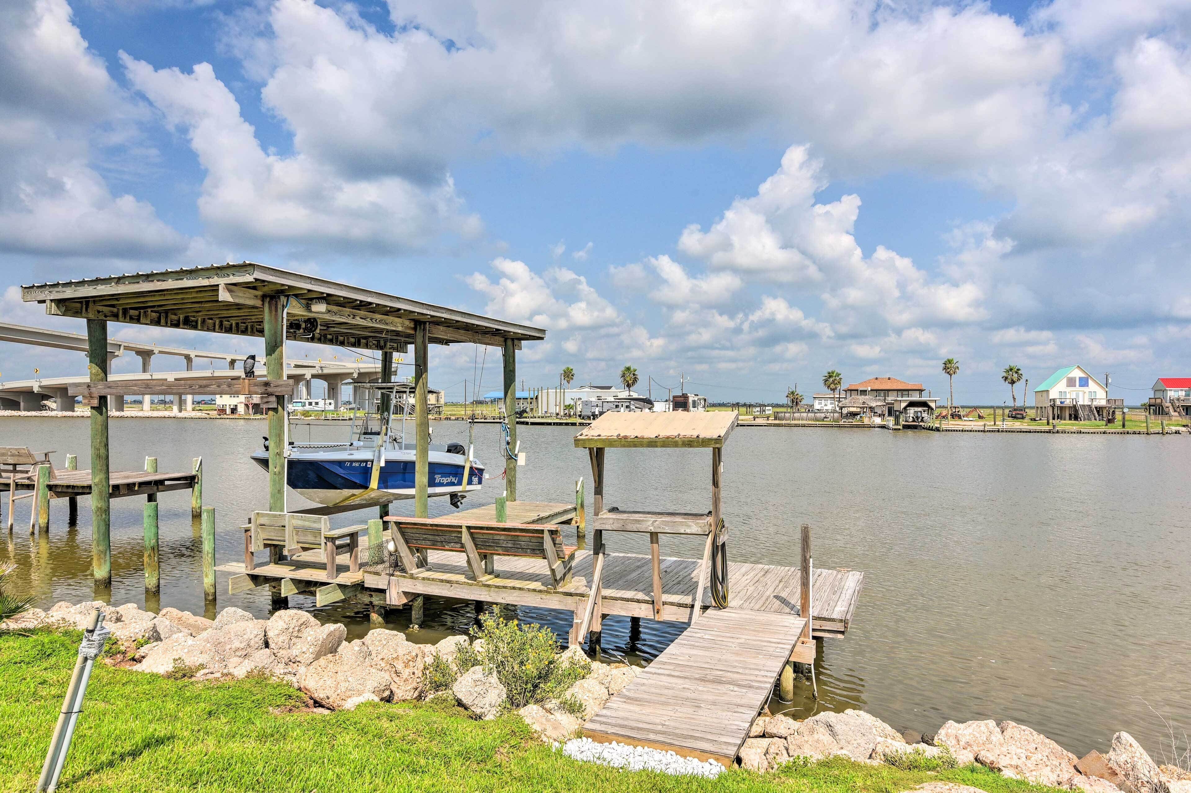 A dock with a covered seating area, a boat, and a small pavilion.