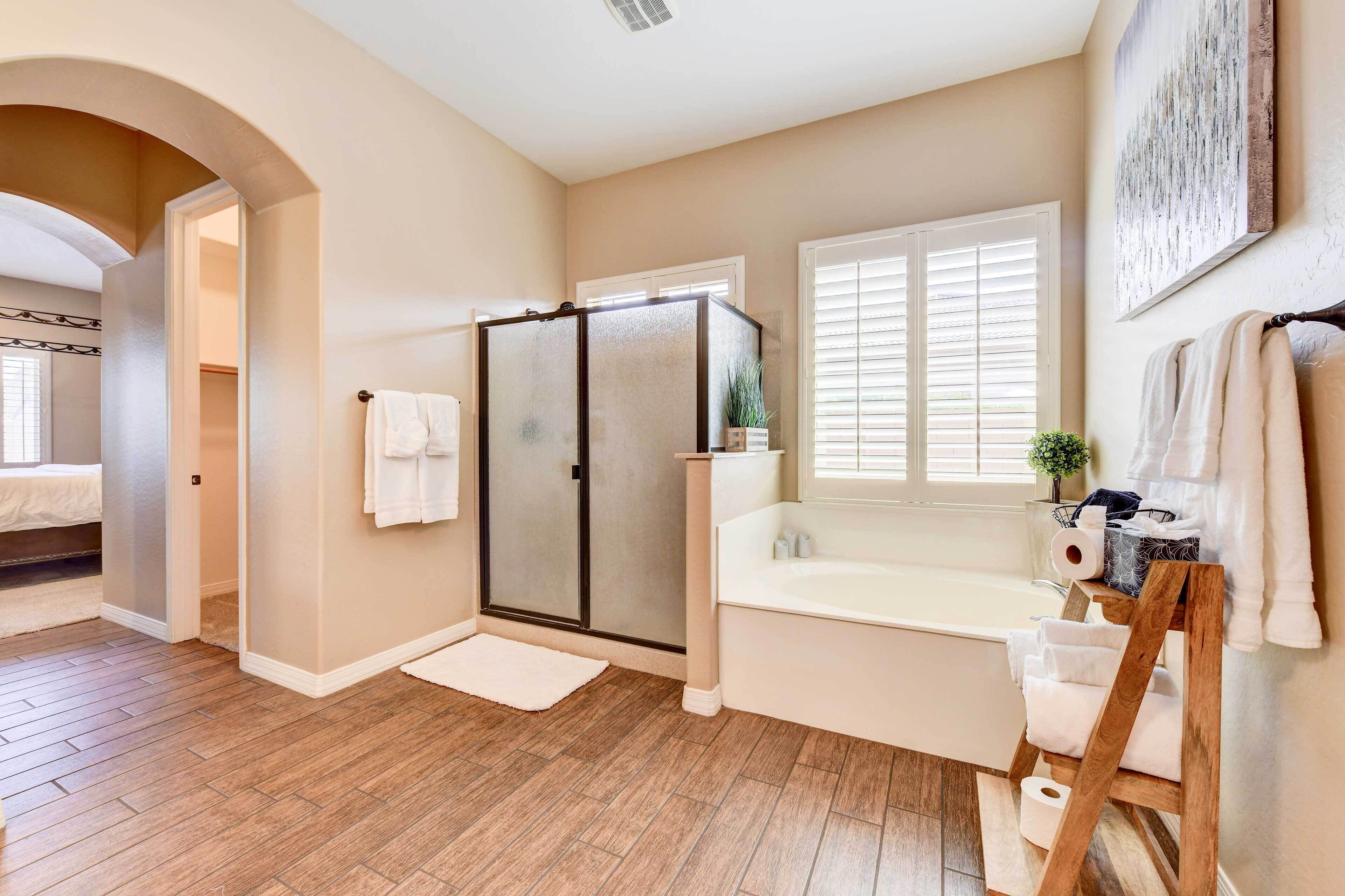 A bathroom with a bathtub, shower, and walk-in closet.