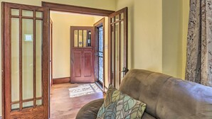 A room with a brown leather sofa, a patterned throw pillow, and a wooden door with glass panels. - Lovely Milwaukee Getaway - Family Friendly! (Milwaukee)